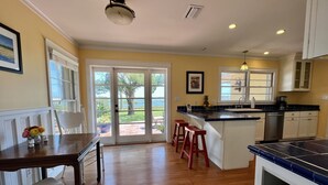 A kitchen with a large island, wooden flooring, and a view through glass doors to a patio area. - An irresistable oceanfront vacation home in the heart of historic St Augustine! (St Augustine)