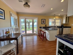 A kitchen with a large island, wooden flooring, and a view through glass doors to a patio area.