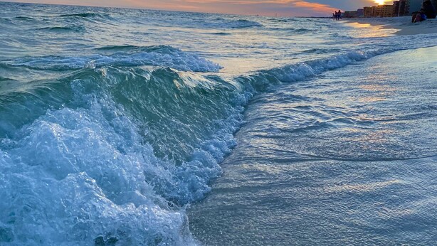 A beach with waves crashing onto the shore, a clear sky, and buildings in the background. - Luxury at it's finest! Penthouse unit overlooking the beautiful Gulf of Mexico! (Fort Walton Beach)