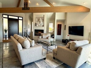 Amplia sala de estar con chimenea, sofás y televisor de pantalla plana.