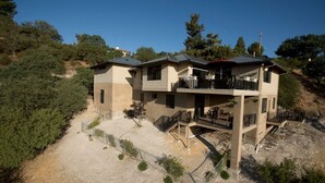 A two-story house with a balcony, surrounded by trees and a hilly landscape. - Hilltop 365: Downtown Luxury ~ Stunning Views ~ Hilltop ~ 3 Blocks To Downtown  (Paso Robles)