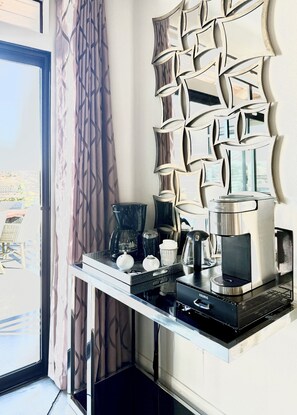 Una kitchenette con cafetera, hervidor y tetera sobre una encimera negra.