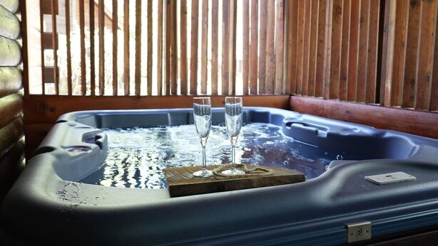 Un jacuzzi con dos vasos de agua, listones de madera al fondo y un panel de control en el lateral.