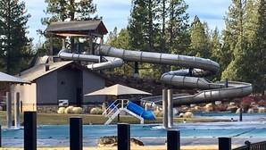 Ein Wasserpark mit Wasserrutsche, einem kleinen Gebäude und einer Rasenfläche.