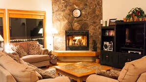 Ein gemütliches Wohnzimmer mit Kamin, zwei Sofas, einem Couchtisch und einer Wand aus Naturstein.