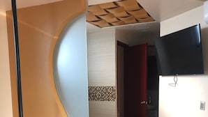 Um banheiro moderno com divisória curva, banheira, vaso sanitário e área de chuveiro.