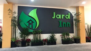 Placa do 'Jard Inn' com logotipo verde apresentando uma casa e uma folha.