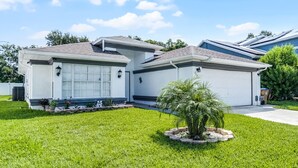 A modern two-story house with a garage, a well-maintained lawn, and a small palm tree in the front yard. - BUENAVENTURA LAKES (263HS) - 3BR 2BA home with pool in a private setting (Kissimmee)