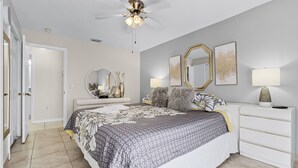 A bedroom with a bed, bedside tables, a ceiling fan, and a door. - BUENAVENTURA LAKES (263HS) - 3BR 2BA home with pool in a private setting (Kissimmee)