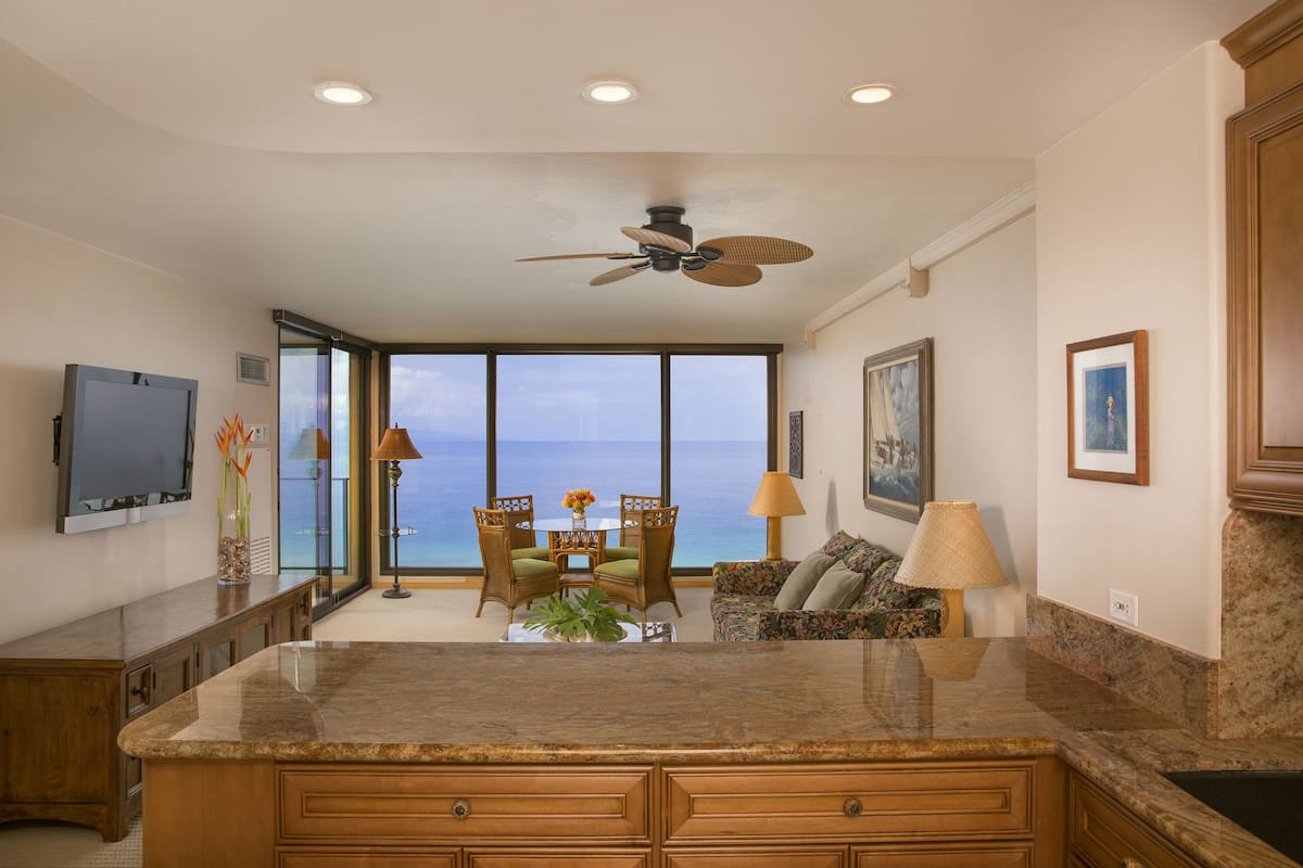 A kitchen with a granite countertop, wooden cabinets, and a ceiling fan.