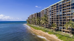 A beachfront hotel with multiple floors, balconies, and a pool area.