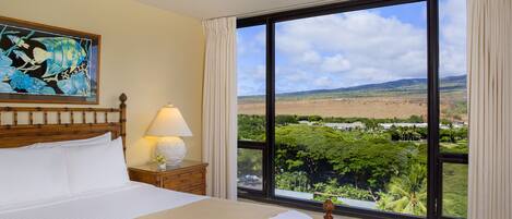 A hotel room with a large window offering a view of a lush landscape.