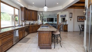 A spacious kitchen with a large island, wooden cabinets, and a modern pendant light. - Phoenix Scottsdale Golf House. NEW! Private Pickle Ball court. Great location. (Phoenix)