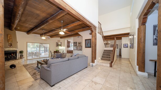 A spacious living area with a large gray sofa, wooden beams, a fireplace, and a staircase leading to an upper level. - Phoenix Scottsdale Golf House. NEW! Private Pickle Ball court. Great location. (Phoenix)