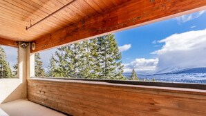 Un balcon en bois avec un banc, donnant sur un paysage enneigé et des arbres.