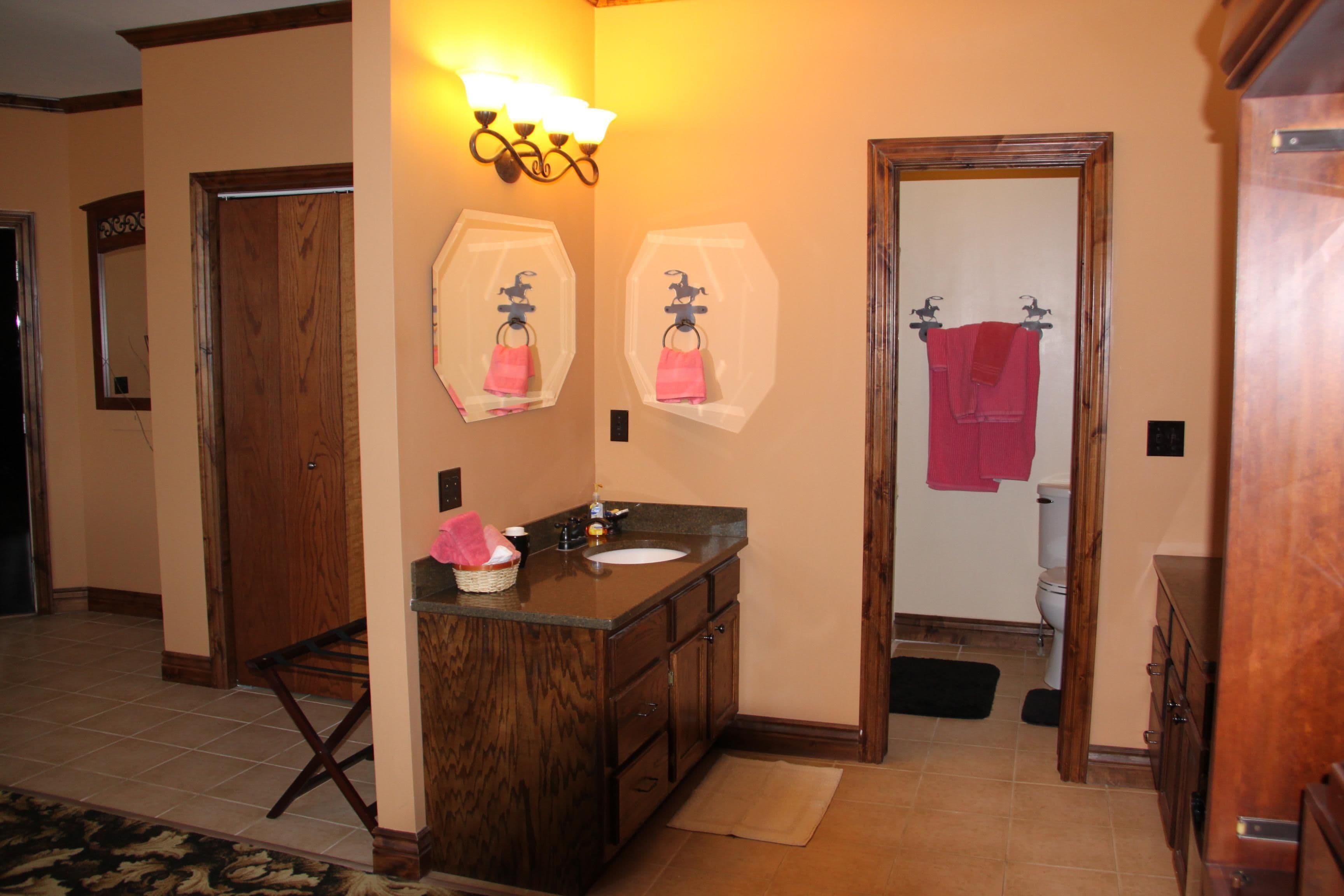 A bathroom with a wooden vanity, two towel racks, a sink, and a mirror.