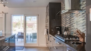 A modern kitchen with a glass door leading to a patio, stainless steel appliances, and a tiled backsplash.