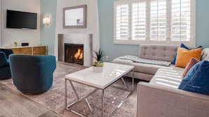 A living room with a fireplace, a sofa, a coffee table, and a TV.