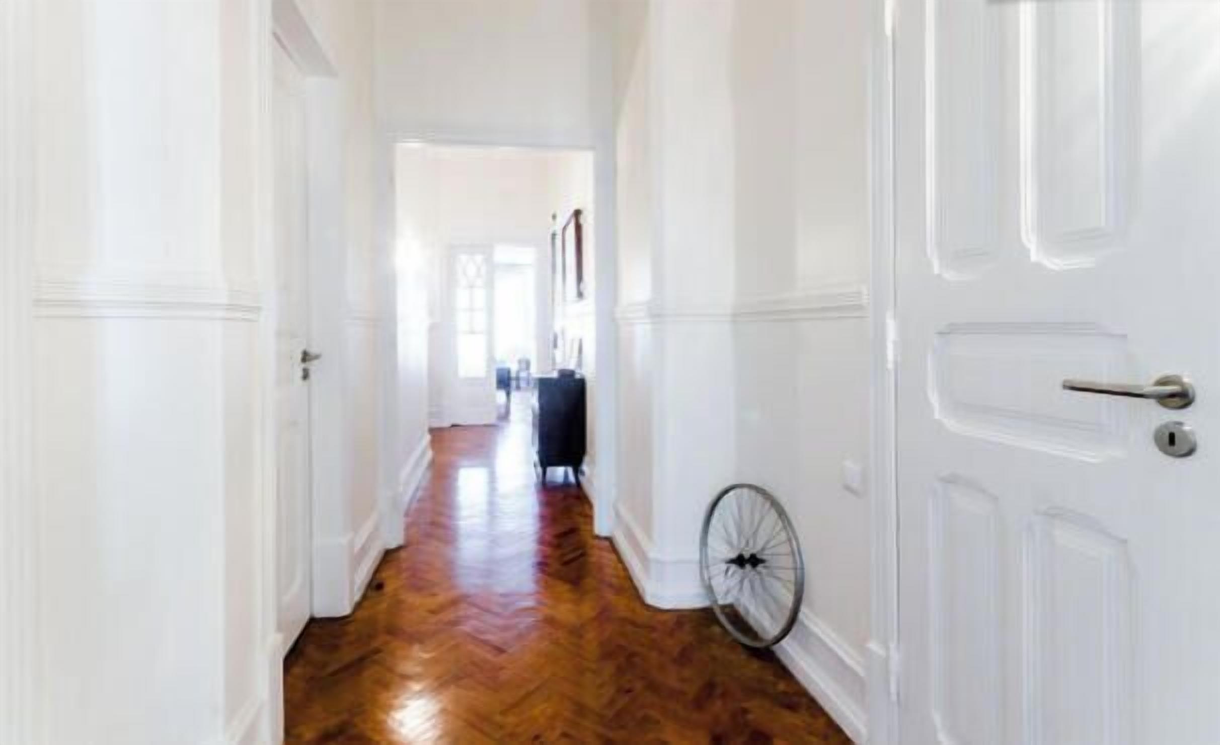 Un couloir avec un plancher en bois et des portes blanches.