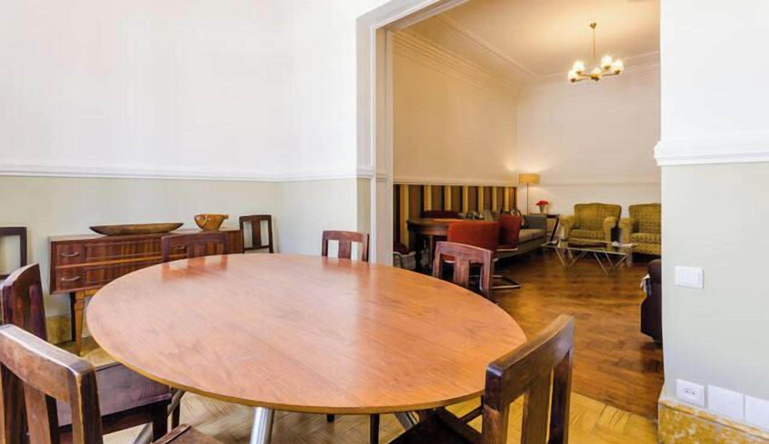 Un grand espace dédié à la salle à manger, avec une grande table et des chaises en bois, un petit coin cuisine équipé d’une cuisinière et de quelques sièges, et un salon avec un canapé et des fauteuils.
