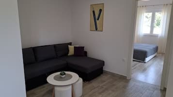 A modern living room with a dark sectional sofa, a small round table, and a painting on the wall.