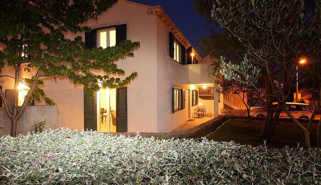 Una casa moderna de dos pisos con una entrada bien iluminada, una escalera visible y un pequeño jardín.