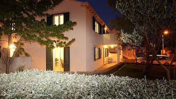 Una casa moderna de dos pisos con una entrada bien iluminada, una escalera visible y un pequeño jardín.