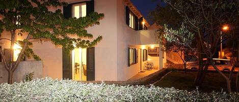 Una moderna casa a due piani con un ingresso ben illuminato, una scala visibile e un piccolo giardino.