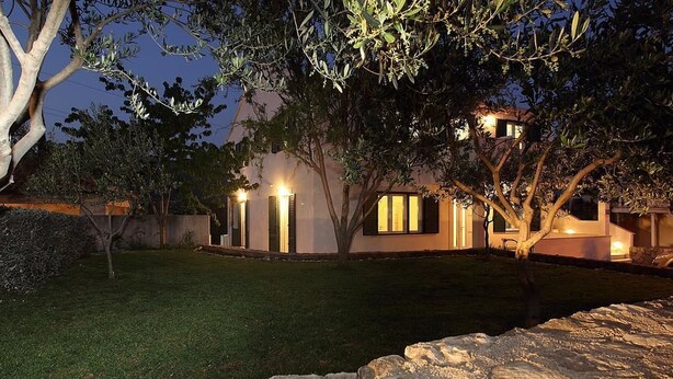 A modern house with a well-maintained lawn and a stone wall in the foreground. - Mocici apartments (Konavle)