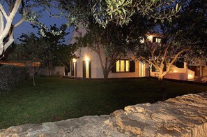 Una casa moderna con césped cuidado y un muro de piedra al frente.