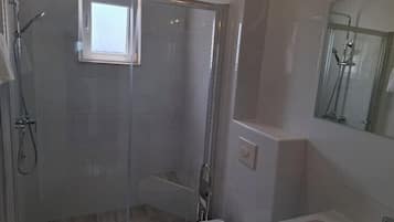 Une salle de bain moderne dotée d’une douche à parois de verre, de toilettes et d’un lavabo.