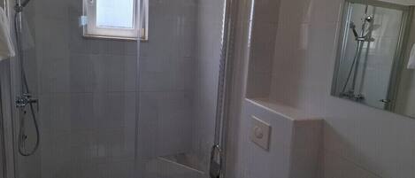 Une salle de bain moderne dotée d’une douche à parois de verre, de toilettes et d’un lavabo.