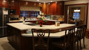 A spacious kitchen with wooden cabinets, a large island, and a dining area with chairs.