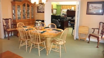 Uma sala de jantar com mesa e cadeiras de madeira, um aparador e um candelabro.