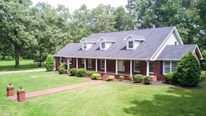 A two-story brick house with a gabled roof, a front porch, and a well-maintained lawn.