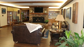 A living room with a fireplace, leather sofa, and a television.