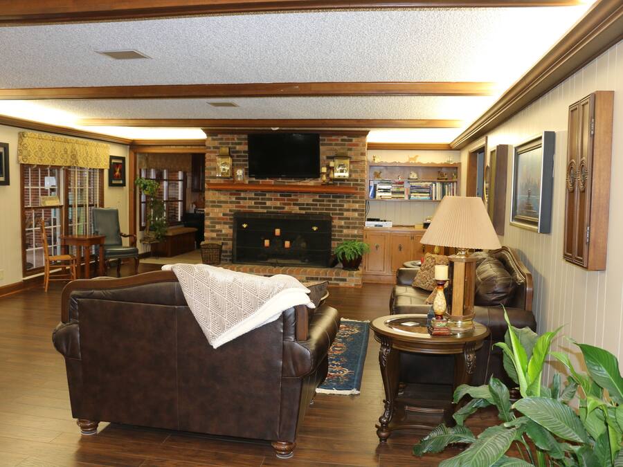 A living room with a fireplace, leather sofa, and a television.