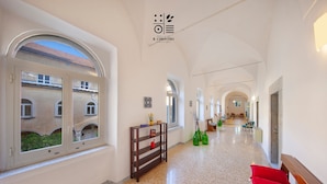 A hotel corridor with arched ceilings, a wooden bench with red cushions, and a small table with decorative items. - Relais il Chiostro Historic Courtyard and Panoramic Terrace near Sorrento (Massa Lubrense)