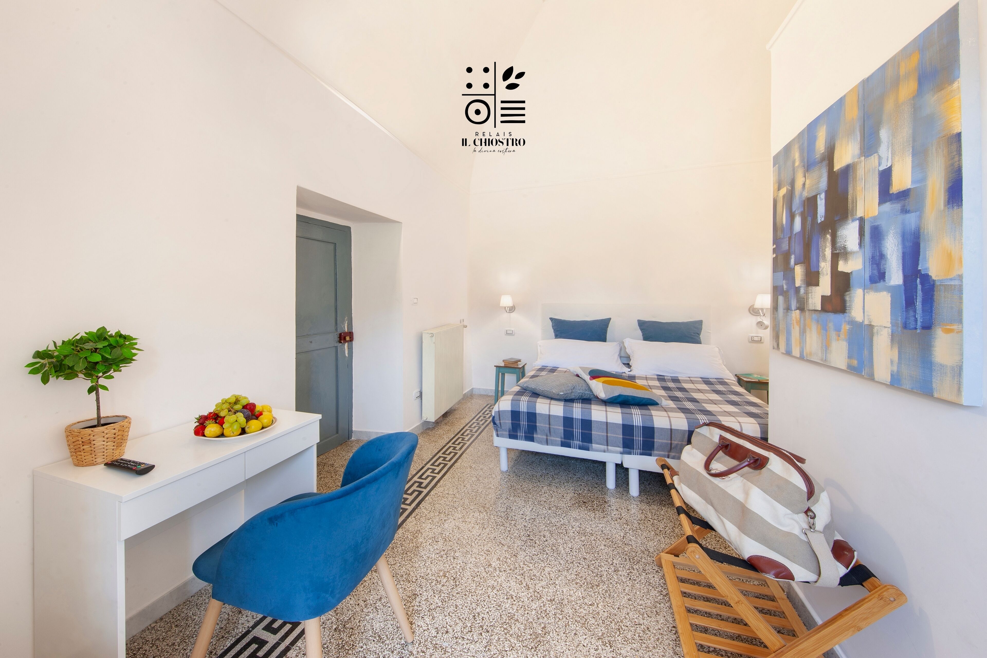A modern bedroom with a bed, bedside table, chair, and a wall-mounted artwork.