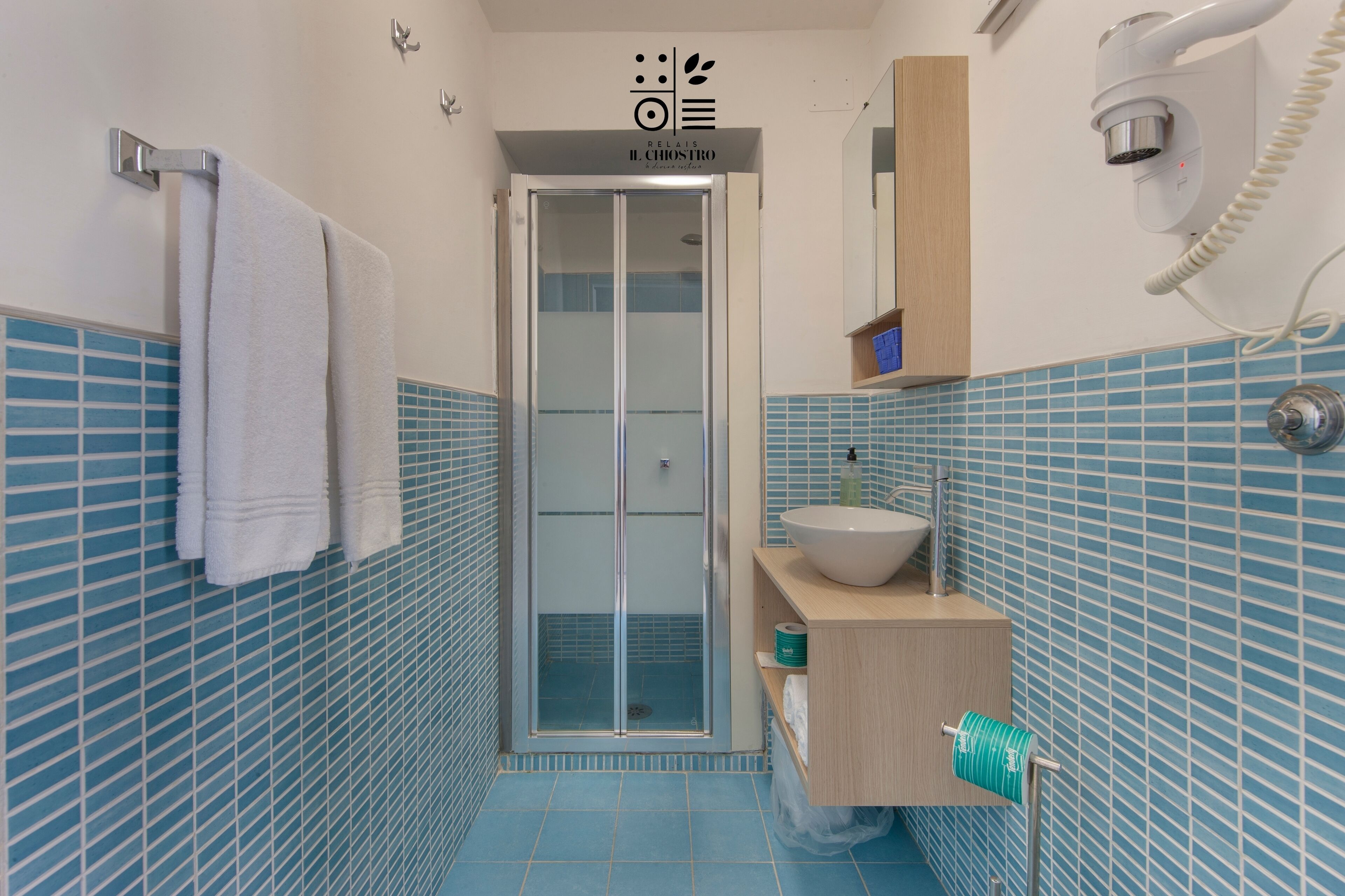 Een badkamer met een douchecabine van glas, een wastafel en een handdoekrek.
