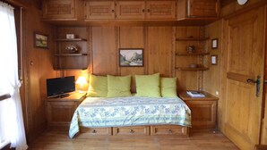 Een houten kamer met een bed, een televisie en een lamp.