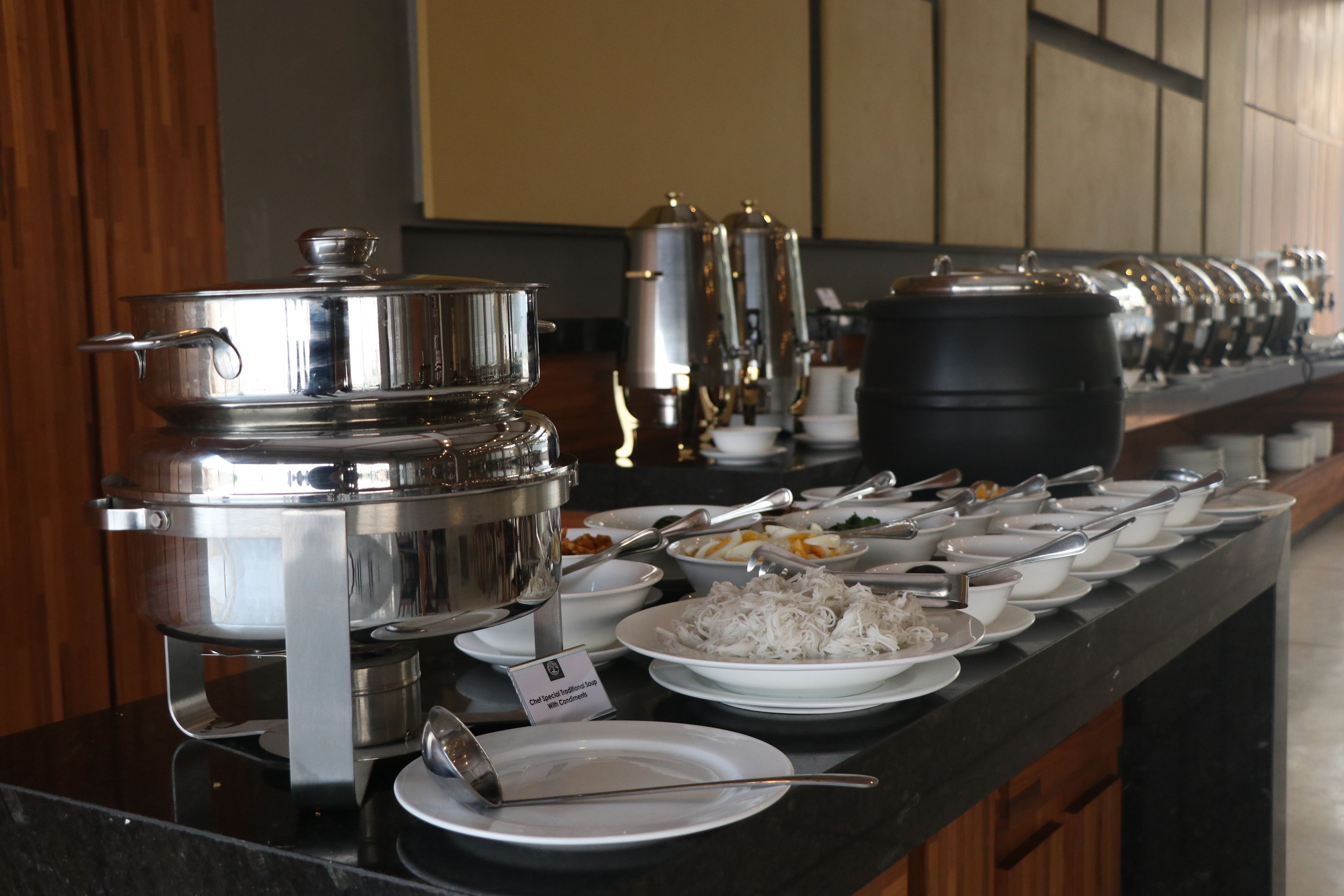 A buffet setup with various food items and serving utensils.