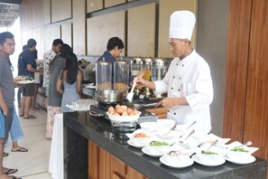 A buffet setup with various food items and a chef serving.