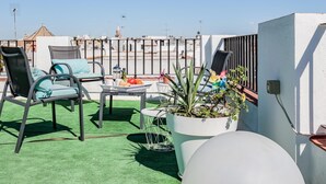 A rooftop terrace with outdoor seating, a table with food, and a view of the cityscape. - Spectacular apartment with private terrace / WIFI (Sevilla)