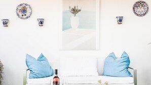 A white sofa with blue cushions, a white coffee table, a bottle of wine, glasses, and snacks. - Spectacular apartment with private terrace / WIFI (Sevilla)
