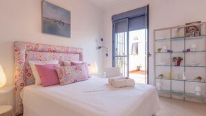 A bedroom with a bed, a glass cabinet with decorative items, and a window with a view. - Spectacular apartment with private terrace / WIFI (Sevilla)