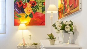 A room with a white cabinet, a small table with a lamp, a vase of white flowers, and two paintings on the wall. - Spectacular apartment with private terrace / WIFI (Sevilla)