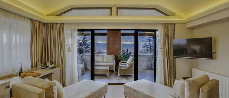 Una sala de estar moderna con dos sofás, una mesa de centro, un televisor y un balcón con mobiliario exterior.