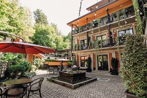 Un patio al aire libre con mesas y sillas, una estatua y una fuente.