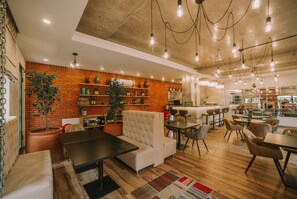 A modern interior with a brick wall, wooden floors, and a mix of seating areas including sofas and tables. - Seventeen Rooms (Telavi)